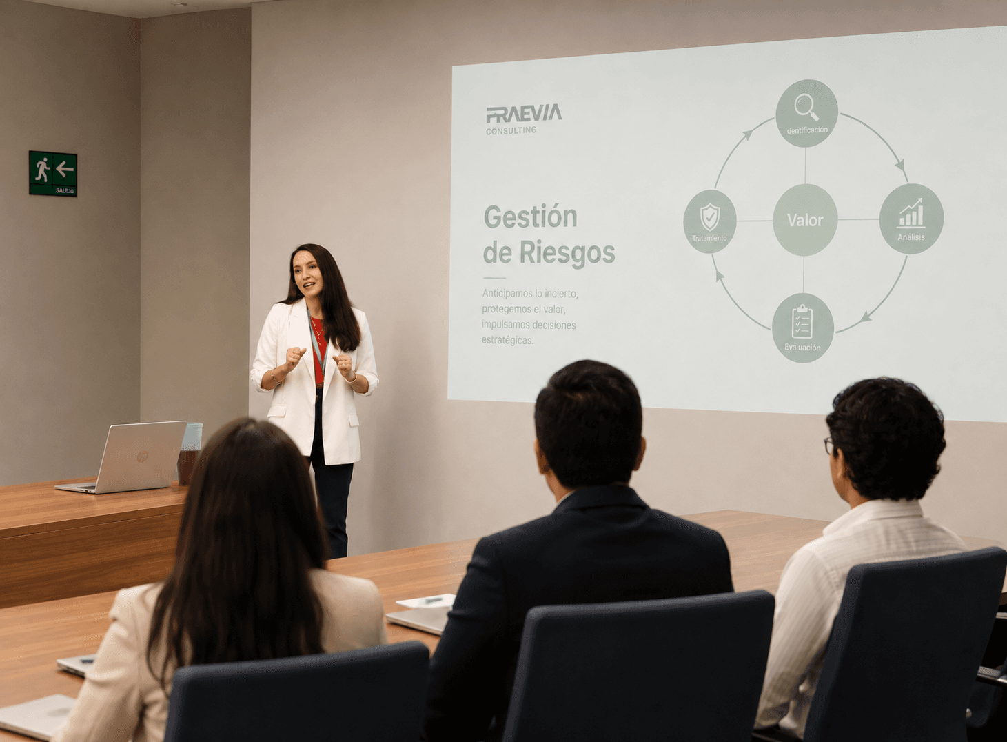 Mujer presenta una diapositiva sobre gestión de riesgos ante un grupo en una oficina.